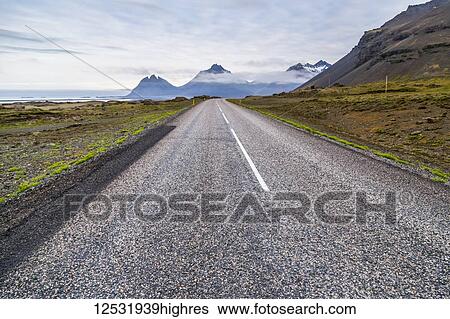 Stock Photograph - The long paved highway leading into the volcanic mountain landscape in the distance; Iceland. Fotosearch