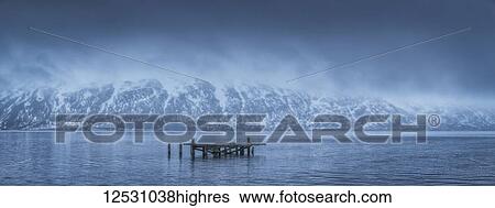 Stock Photograph - The old dock in Djupavik, Iceland in moody weather with clouds hanging low over the mountains; Djupavik, West Fjords, Iceland. Fotosearch