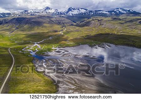 Stock Photograph - The road winding around Snaefellsness Peninsula with a braided river running into the ocean; Iceland. Fotosearch