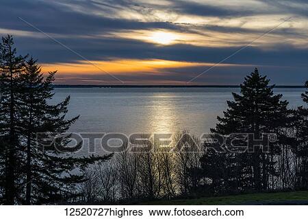 Stock Photograph - The sun sinks low over the Columbia River; Chinook, Washington, United States of America. Fotosearch