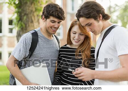 Three friends standing and talking on the university campus with their smart phone and laptop; Edmonton, Alberta, Canada View Large Photo Image Stock Photograph - Three friends standing and talking on the university campus with their smart phone and laptop; Edmonton, Alberta, Canada. Fotosearch