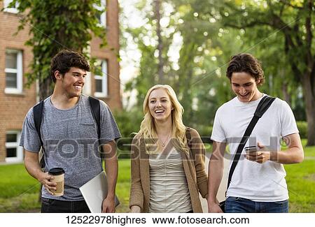 Stock Photograph - Three friends walking and talking on the university campus; Edmonton, Alberta, Canada. Fotosearch