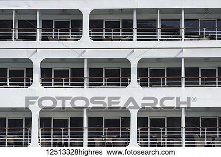 Stock Photograph - Three levels on the side of a boat with chairs on the balconies and glass walls; Kotor, Opstina Kotor, Monte. Fotosearch