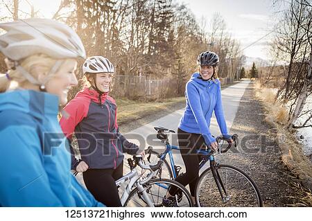 Three young women on their bicycles on a trail at sunrise; Anchorage, Alaska, United States of America View Large Photo Image Stock Photograph - Three young women on their bicycles on a trail at sunrise; Anchorage, Alaska, United States of America. Fotosearch