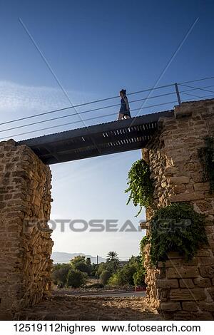 Stock Photograph - Tourist walking over the city wall; Alcudia, Mallorca, Balearic Islands, Spain. Fotosearch