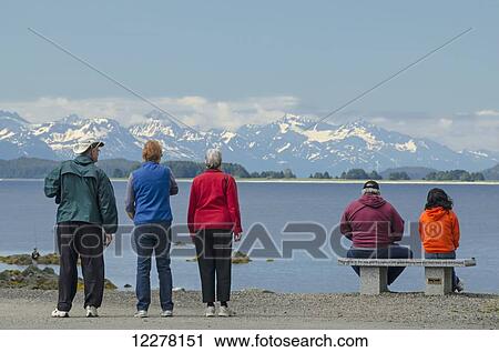 Tourists looking across Lynn Canal at the Chilkat Mountains at the Shrine of St. Therese near Juneau, Southeast Alaska View Large Photo Image Stock Image - Tourists looking across Lynn Canal at the Chilkat Mountains at the Shrine of St. Therese near Juneau, Southeast Alaska. Fotosearch