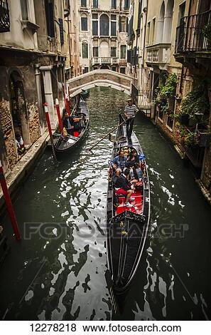 Stock Photo - Tourists punting through the narrow canals of Venice; Venice, Italy. Fotosearch