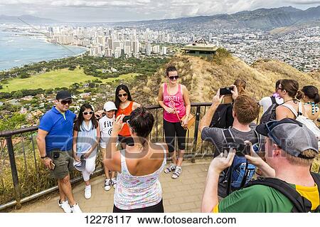 Tourists taking family photos on Diamond Head with Honolulu Waikiki in the background; Honolulu, Oahu, Hawaii, United States of America View Large Photo Image Stock Photo - Tourists taking family photos on Diamond Head with Honolulu Waikiki in the background; Honolulu, Oahu, Hawaii, United States of America. Fotosearch