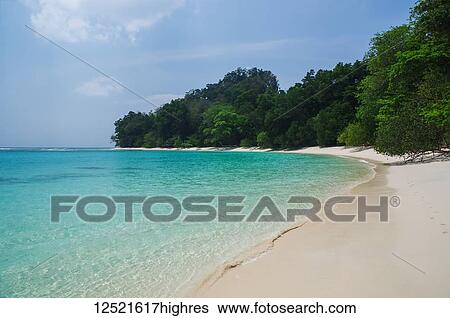 Stock Photograph - Tropical beach with white sand, blue sky and turquoise water; Andaman Islands, India. Fotosearch
