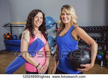 Stock Photograph - Two attractive middle-aged women posing for the camera after working out at a fitness class in a gym; Spruce Grove, Alberta, Canada. Fotosearch