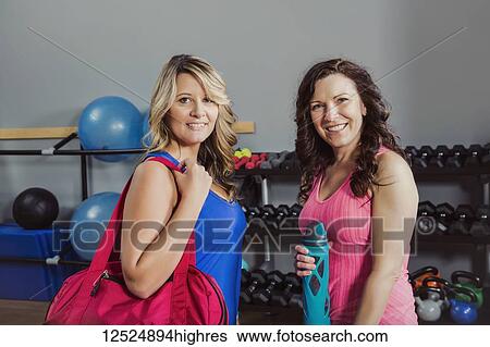 Stock Photograph - Two attractive middle-aged women posing for the camera after working out at a fitness class in a gym; Spruce Grove, Alberta, Canada. Fotosearch
