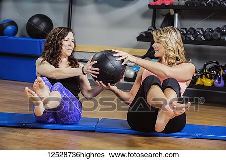 Two attractive middle-aged women working out at the gym together with a medicine ball; Spruce Grove, Alberta, Canada View Large Photo Image Stock Photograph - Two attractive middle-aged women working out at the gym together with a medicine ball; Spruce Grove, Alberta, Canada. Fotosearch