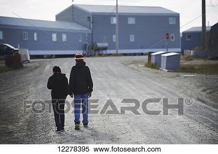 Stock Photography - Two boys walking on dirt road; Cambridge Bay, Victoria Island, Nunavut, Canada. Fotosearch