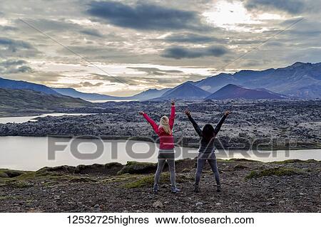 Two female travellers celebrate their hike and embrace the excitement of this beautiful nature viewpoint in Western Iceland; Iceland View Large Photo Image Stock Photograph - Two female travellers celebrate their hike and embrace the excitement of this beautiful nature viewpoint in Western Iceland; Iceland. Fotosearch