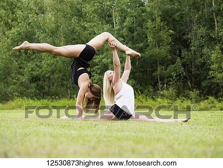 Two Teenage Gymnists Practicing Their Routines Outdoors In A Park And Doing A Handstand Straddle Balance While The Other Partner Does A Split; Edmonton, Alberta, Canada View Large Photo Image Stock Photograph - Two Teenage Gymnists Practicing Their Routines Outdoors In A Park And Doing A Handstand Straddle Balance While The Other Partner Does A Split; Edmonton, Alberta, Canada. Fotosearch