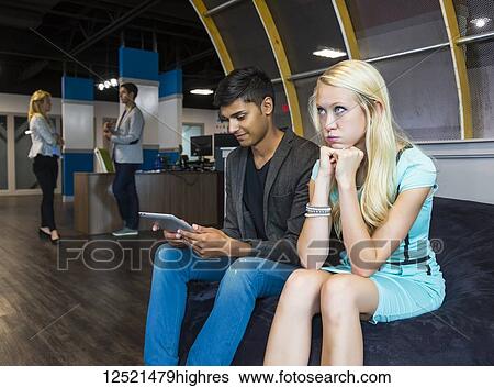 Stock Photograph - Two young millennial business professionals have a disagreement in their place of work; Sherwood Park, Alberta, Canada. Fotosearch