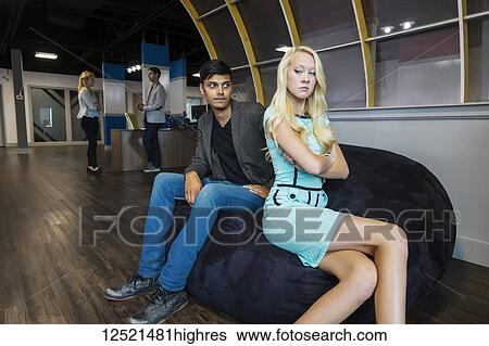 Stock Photograph - Two young millennial business professionals have a disagreement in their place of work; Sherwood Park, Alberta, Canada. Fotosearch