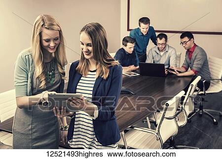 Two young millennial business professionals looking at a pad while working together in a conference room with their piers; Sherwood Park, Alberta, Canada View Large Photo Image Stock Photograph - Two young millennial business professionals looking at a pad while working together in a conference room with their piers; Sherwood Park, Alberta, Canada. Fotosearch