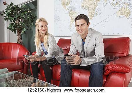 Two young millennial business professionals in the lobby of their workplace using their smart phones while taking a break and one of them looking at the camera; Sherwood Park, Alberta, Canada View Large Photo Image Stock Photograph - Two young millennial business professionals in the lobby of their workplace using their smart phones while taking a break and one of them looking at the camera; Sherwood Park, Alberta, Canada. Fotosearch