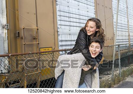 Two young women in a playful pose beside a train car; New Westminster, British Columbia, Canada View Large Photo Image Stock Photograph - Two young women in a playful pose beside a train car; New Westminster, British Columbia, Canada. Fotosearch