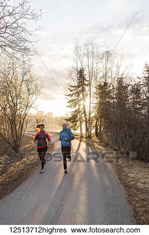Two young women running on a trail at sunrise; Anchorage, Alaska, United States of America View Large Photo Image Stock Photograph - Two young women running on a trail at sunrise; Anchorage, Alaska, United States of America. Fotosearch