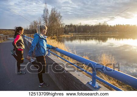 Two young women stretching on a trail at the water's edge; Anchorage, Alaska, United States of America View Large Photo Image Stock Photograph - Two young women stretching on a trail at the water's edge; Anchorage, Alaska, United States of America. Fotosearch