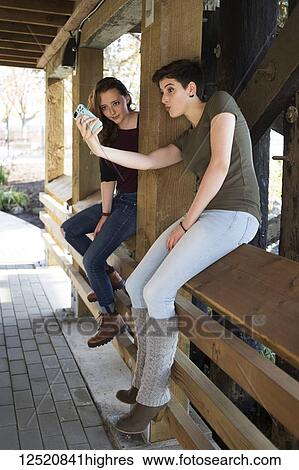 Two young women using a smart phone and being silly taking a self-portrait; New Westminster, British Columbia, Canada View Large Photo Image Stock Photograph - Two young women using a smart phone and being silly taking a self-portrait; New Westminster, British Columbia, Canada. Fotosearch