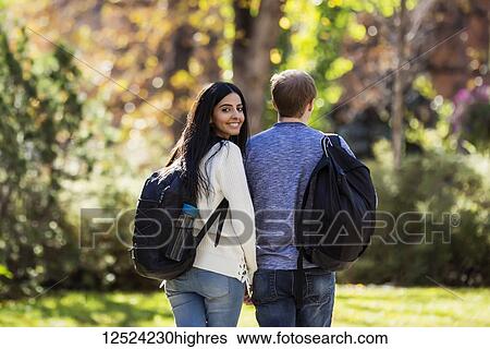 University student couple walking on a path holding hands, the young woman of Lebanese ethnicity looking back at the camera; Edmonton, Alberta, Canada View Large Photo Image Stock Photograph - University student couple walking on a path holding hands, the young woman of Lebanese ethnicity looking back at the camera; Edmonton, Alberta, Canada. Fotosearch
