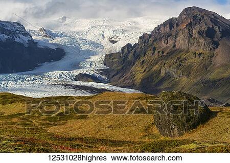 Stock Photograph - View of a large glacier and the mountains along the South coast of Iceland, part of the Vatnajokull ice cap; Iceland. Fotosearch
