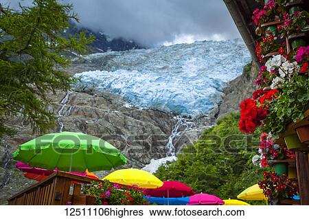Stock Photograph - View of Bossons Glacier with colourful umbrellas and flowers from Chalet du Glacier; Chamonix-Mont-Blanc, Haute-Savoie, France. Fotosearch