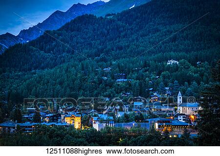 Stock Photograph - View of Courmayeur city center and mountains at dusk; Courmayeur, Aosta Valley, Italy. Fotosearch