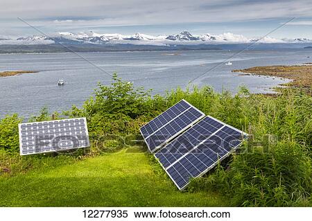 Stock Photography - View of solar panels on Shelter Island with Chilkat Mountain Range in the background near Juneau, Southeast Alaska, Summer.. Fotosearch