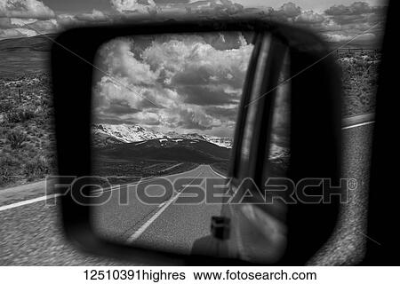 View of the highway and mountains, behind from a vehicle's rear view mirror out the side of the driver's door View Large Photo Image Stock Photograph - View of the highway and mountains, behind from a vehicle's rear view mirror out the side of the driver's door. Fotosearch
