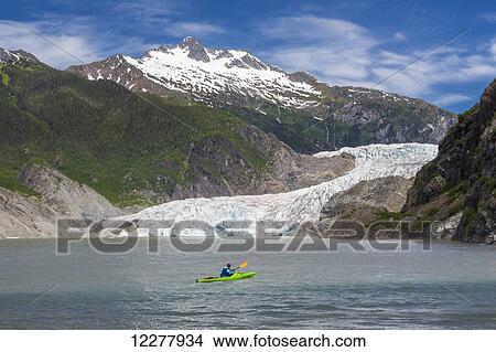 View of the Mendenhall Glacier with a kayaker on Mendenhall Lake in the foreground near Juneau, Southeast Alaska, Summer. View Large Photo Image Picture - View of the Mendenhall Glacier with a kayaker on Mendenhall Lake in the foreground near Juneau, Southeast Alaska, Summer.. Fotosearch