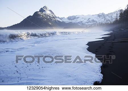 Stock Photograph - Waves crashing onto the beach along the coast along the Kenai Mountains, Kachemak Bay State Park; Alaska, United States of America. Fotosearch