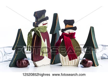 Stock Photograph - Wooden snowmen and trees as Christmas decorations on a white surface. Fotosearch