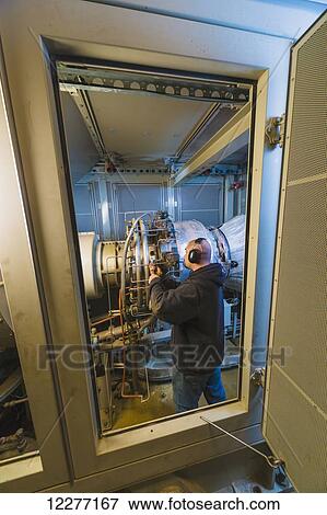 Worker working on an electrical power plant, gas turbine generator and drive shaft, Prudhoe Bay, Arctic Alaska, USA, Summer View Large Photo Image Stock Photo - Worker working on an electrical power plant, gas turbine generator and drive shaft, Prudhoe Bay, Arctic Alaska, USA, Summer. Fotosearch