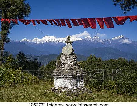 Stock Photograph - Worn and weathered Buddhist monument on a mountainside with red prayer flags and a view of the rugged, snow-capped Himalayas; Sikkim, India. Fotosearch