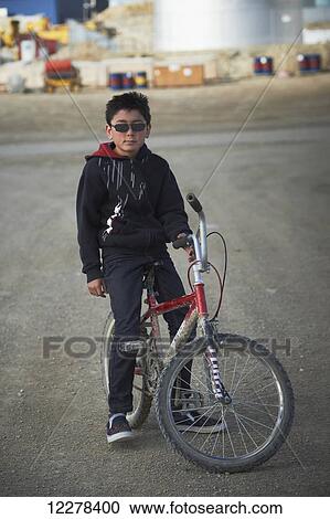 Stock Image - Young boy on a bike; Cambridge Bay, Nunavut, Canada. Fotosearch