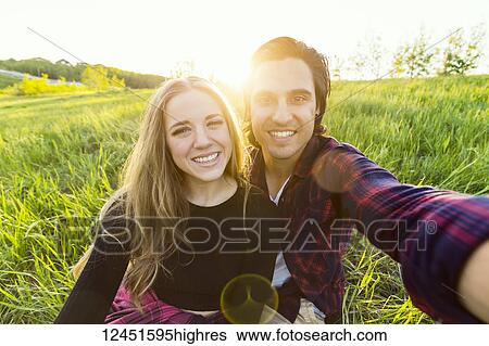 Young couple in a park posing for a self-portrait with their cell phone; Edmonton, Alberta, Canada View Large Photo Image Stock Photograph - Young couple in a park posing for a self-portrait with their cell phone; Edmonton, Alberta, Canada. Fotosearch