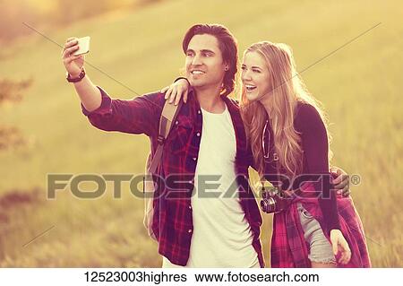 Young couple in a park posing for a self-portrait with their cell phone; Edmonton, Alberta, Canada View Large Photo Image Stock Photograph - Young couple in a park posing for a self-portrait with their cell phone; Edmonton, Alberta, Canada. Fotosearch