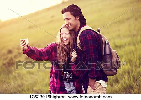 Young couple in a park posing for a self-portrait with their cell phone; Edmonton, Alberta, Canada View Large Photo Image Stock Photograph - Young couple in a park posing for a self-portrait with their cell phone; Edmonton, Alberta, Canada. Fotosearch