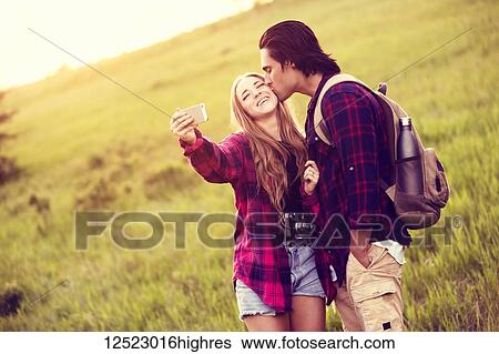 Young couple in a park posing for a self-portrait with their cell phone; Edmonton, Alberta, Canada View Large Photo Image Stock Photograph - Young couple in a park posing for a self-portrait with their cell phone; Edmonton, Alberta, Canada. Fotosearch