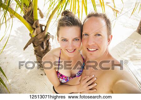 Young couple taking a self-portrait on a tropical beach; Negril, Jamaica View Large Photo Image Stock Photograph - Young couple taking a self-portrait on a tropical beach; Negril, Jamaica. Fotosearch