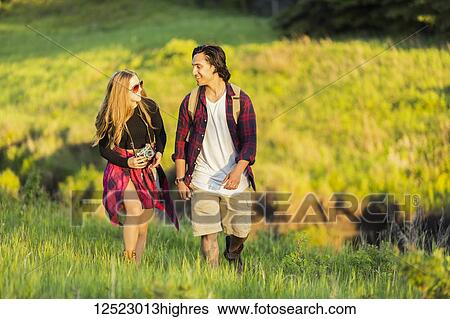 Young couple walking together in a city park; Edmonton, Alberta, Canada View Large Photo Image Stock Photograph - Young couple walking together in a city park; Edmonton, Alberta, Canada. Fotosearch
