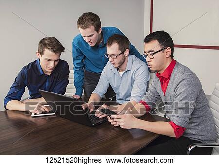 Young men who are millennial business professionals working together in a conference room in a high tech modern business; Sherwood Park, Alberta, Canada View Large Photo Image Stock Photograph - Young men who are millennial business professionals working together in a conference room in a high tech modern business; Sherwood Park, Alberta, Canada. Fotosearch