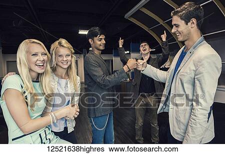 Stock Photograph - Young millennial business co-workers celebrating a success in the workplace; Sherwood Park, Alberta, Canada. Fotosearch
