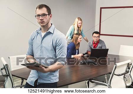 Young millennial business man posing for the camera in a conference room of young professionals working together in a modern place of business; Sherwood Park, Alberta, Canada View Large Photo Image Stock Photograph - Young millennial business man posing for the camera in a conference room of young professionals working together in a modern place of business; Sherwood Park, Alberta, Canada. Fotosearch