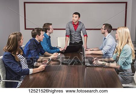Young millennial business man speaking to a group of young professionals in a conference room in a place of business; Sherwood Park, Alberta, Canada View Large Photo Image Stock Photograph - Young millennial business man speaking to a group of young professionals in a conference room in a place of business; Sherwood Park, Alberta, Canada. Fotosearch