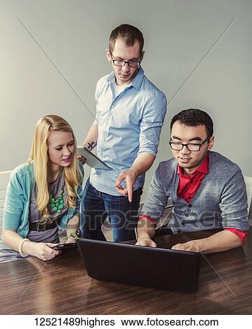 Young millennial business professionals working together in a conference room in a high tech modern business; Sherwood Park, Alberta, Canada View Large Photo Image Stock Photograph - Young millennial business professionals working together in a conference room in a high tech modern business; Sherwood Park, Alberta, Canada. Fotosearch
